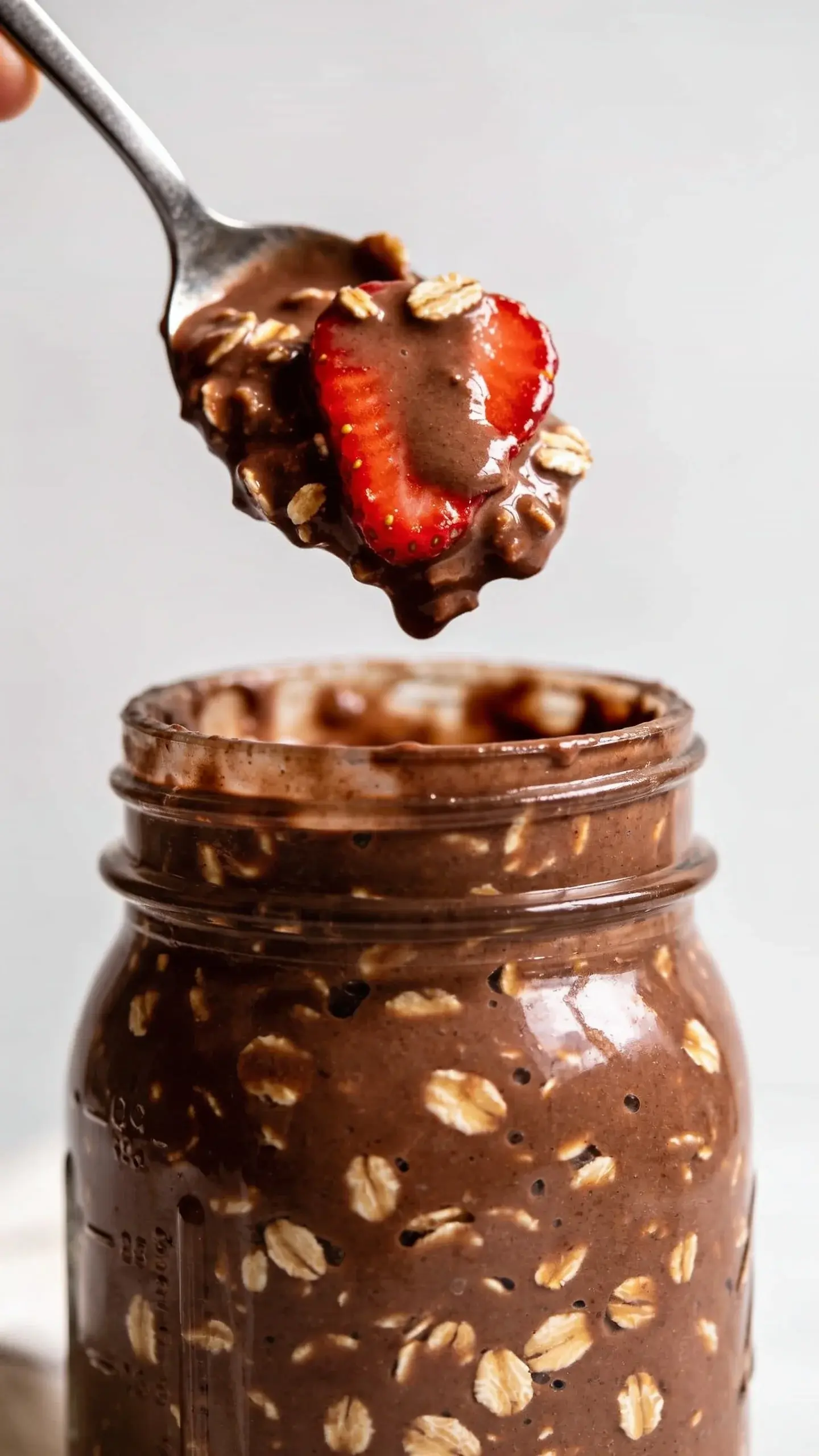 Spoonful of chocolate strawberry overnight oats above the jar