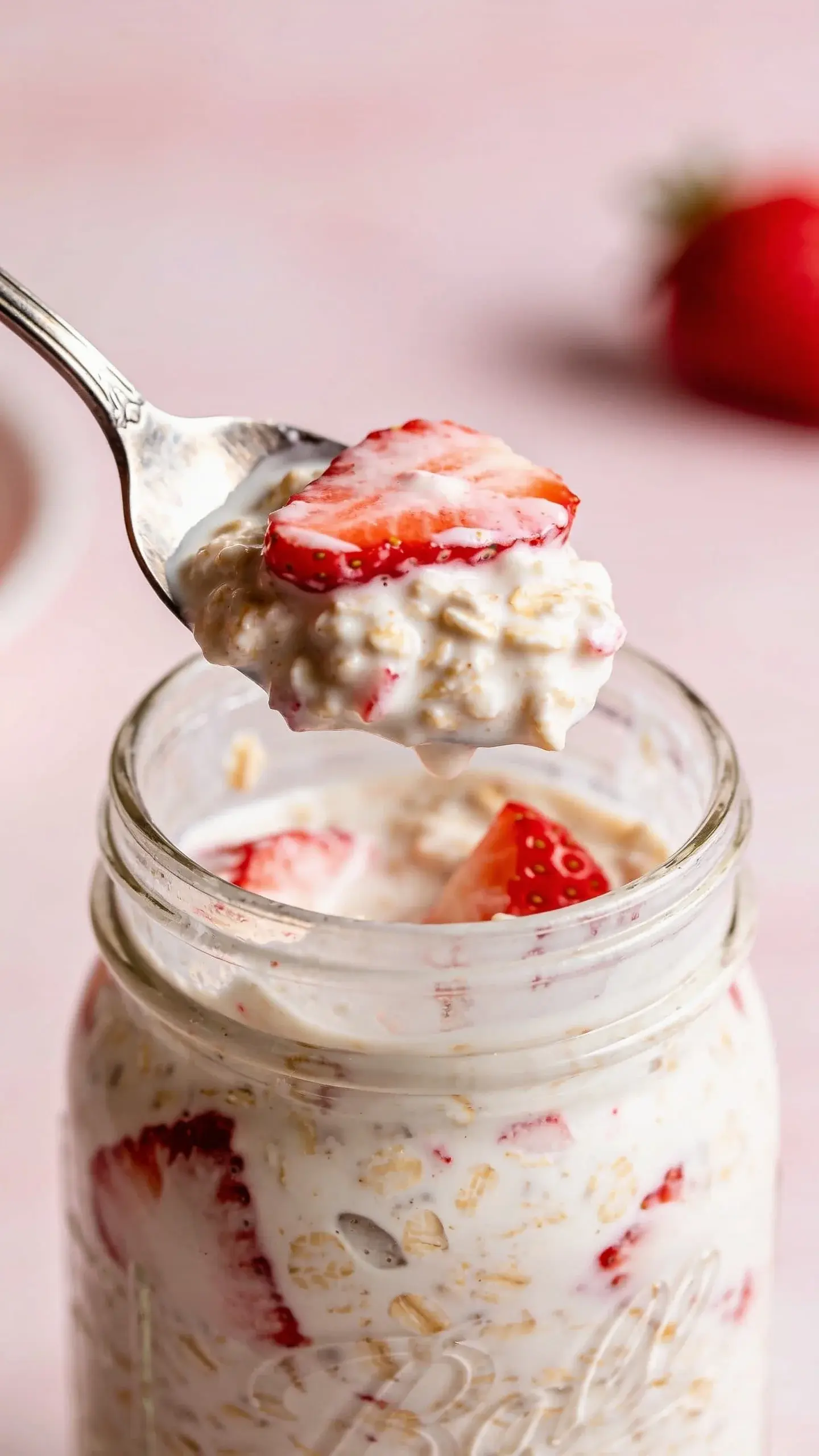Spoonful of creamy strawberry cheesecake overnight oats above the jar