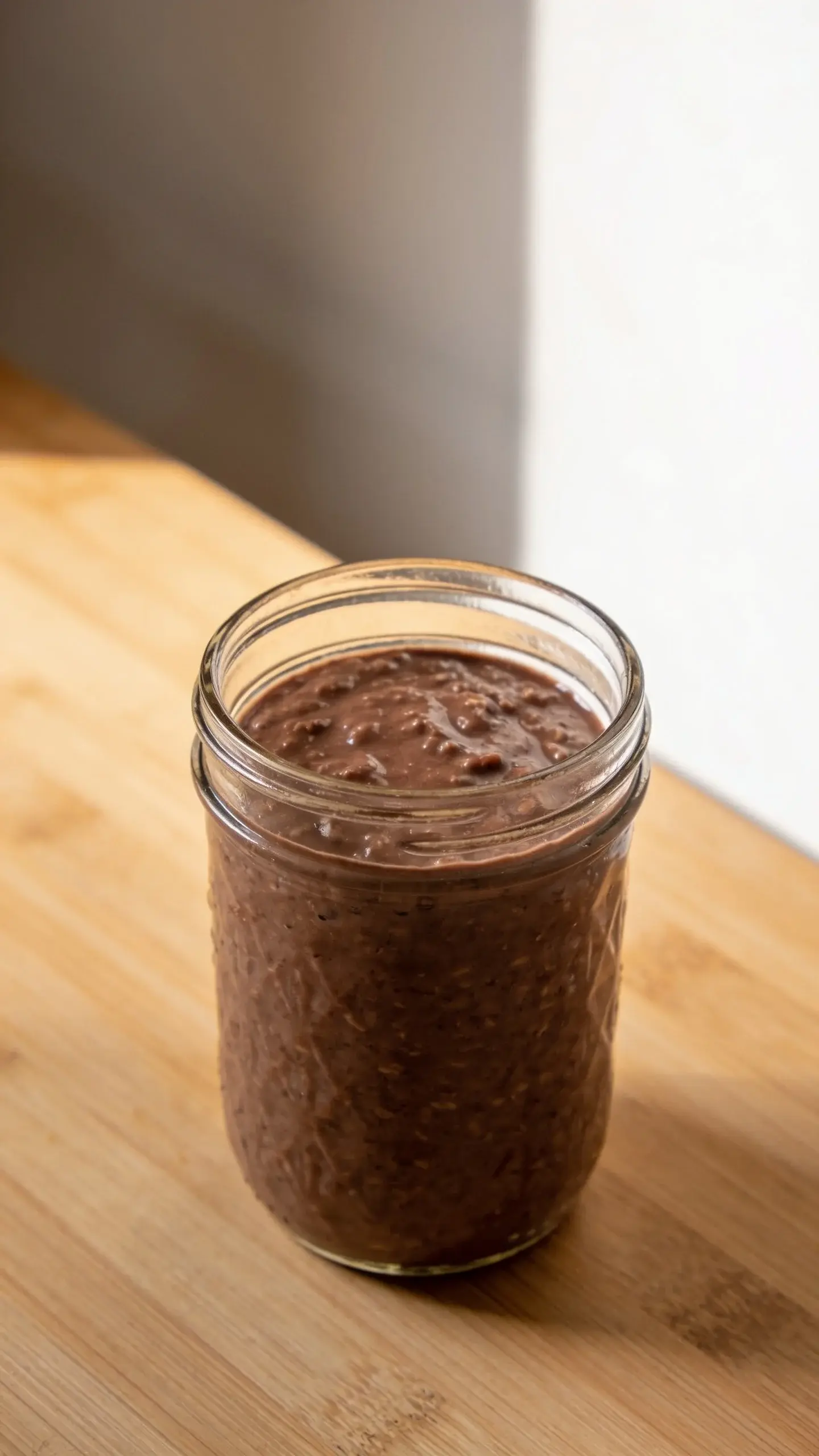 Glass jar of thick chocolate brownie batter overnight oats on a wooden table