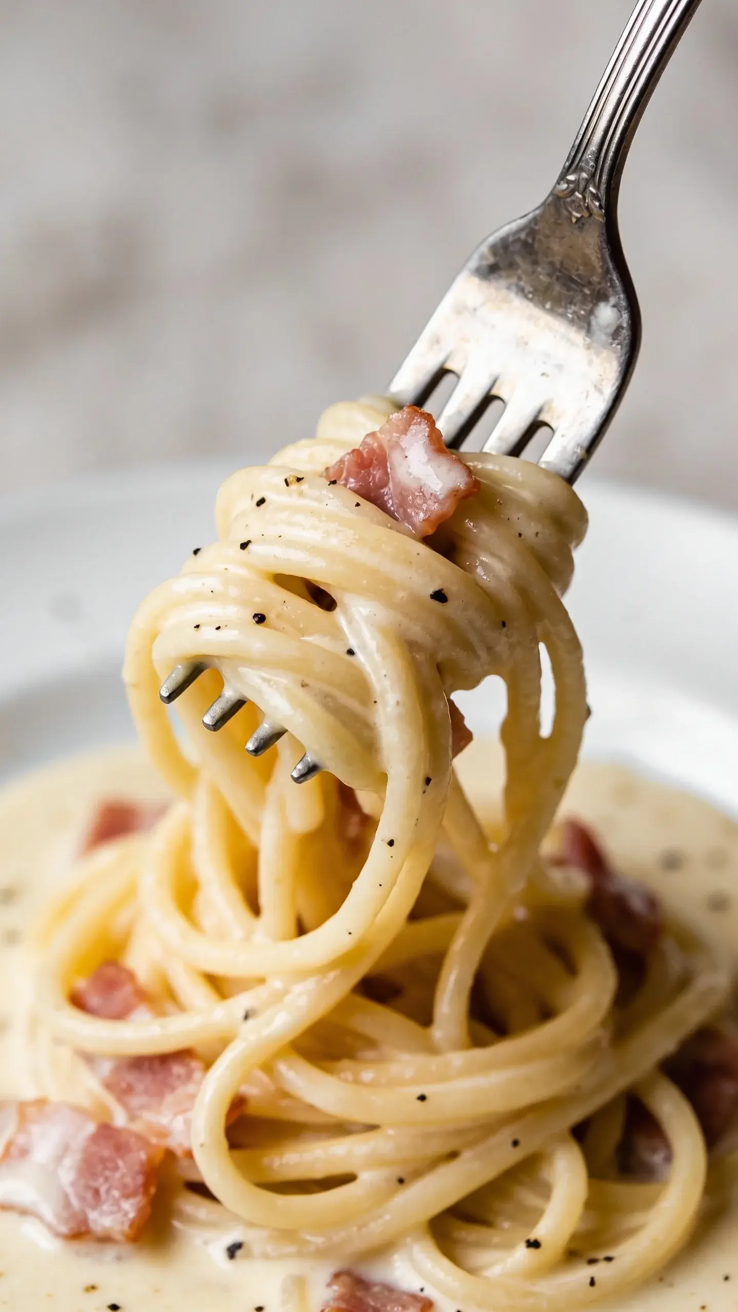 Fork twirling spaghetti carbonara with bacon and Parmesan